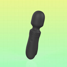 A matte black personal massager with a rounded head and textured grip, shown on a green gradient background with a faint grid pattern.