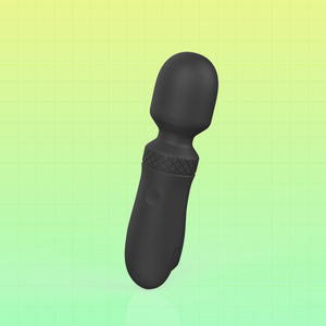 A matte black personal massager with a rounded head and textured grip, shown on a green gradient background with a faint grid pattern.